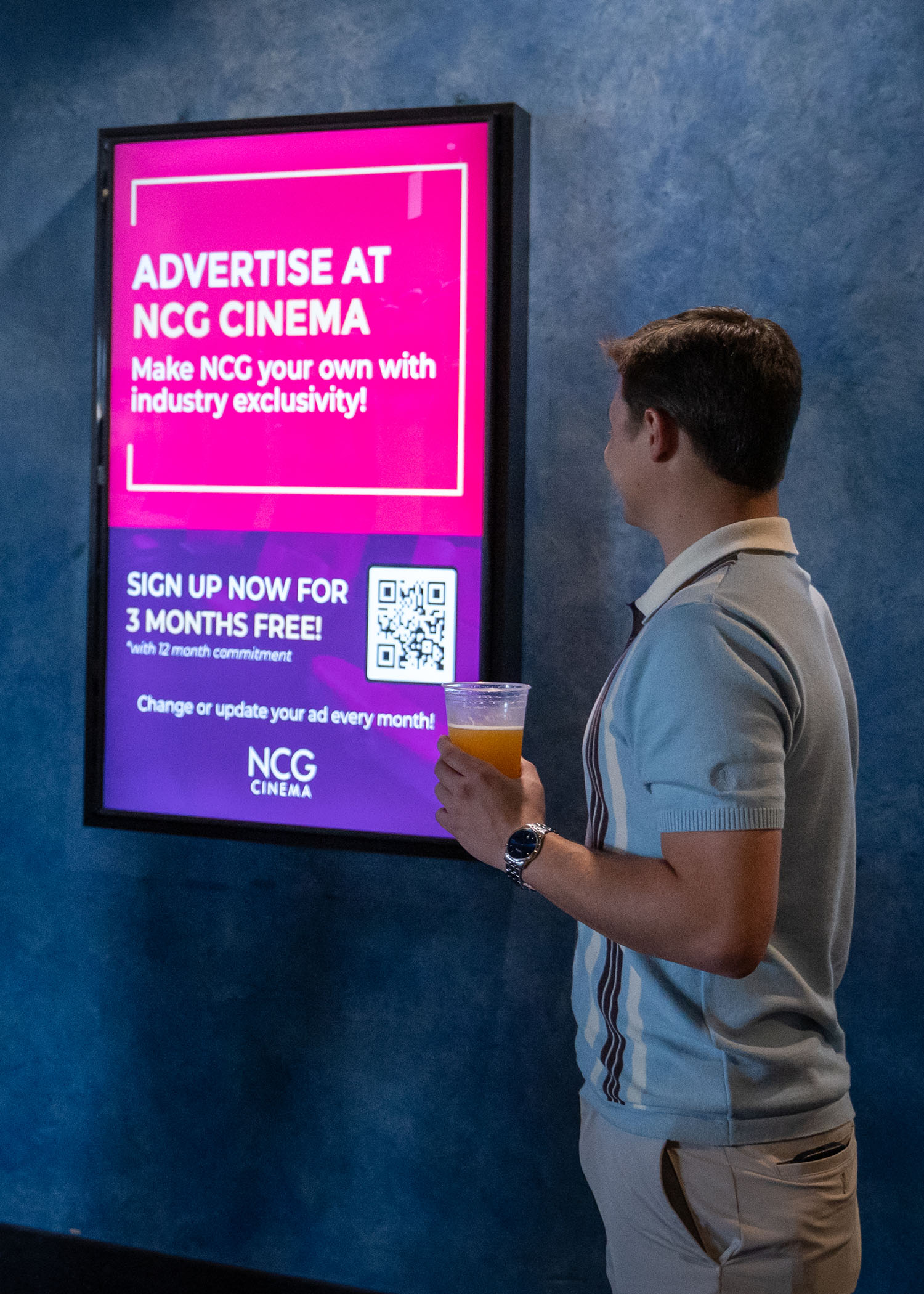 people looking at digital ads in a theater lobby